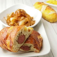 Pretzel Wrapped Brats with Cider Braised Onions - Jamie Geller image